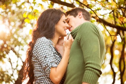 Happy couple kissing in the park during fall
