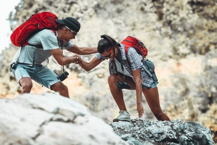Young couple hiking and climbing at the mountain to represent Dr. Karen Gless' blog Work it Out – with a Lot Less Pain