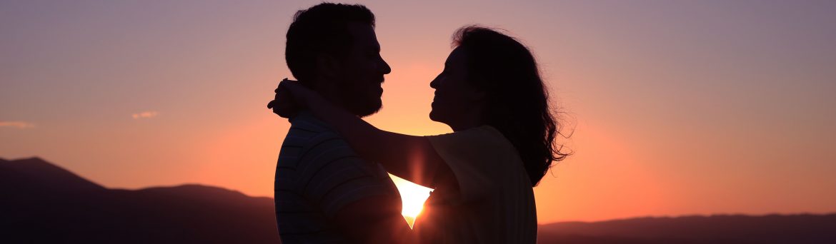 Couple Hugging with the Sunset Between Them