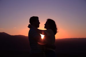 Couple Hugging with the Sunset Between Them